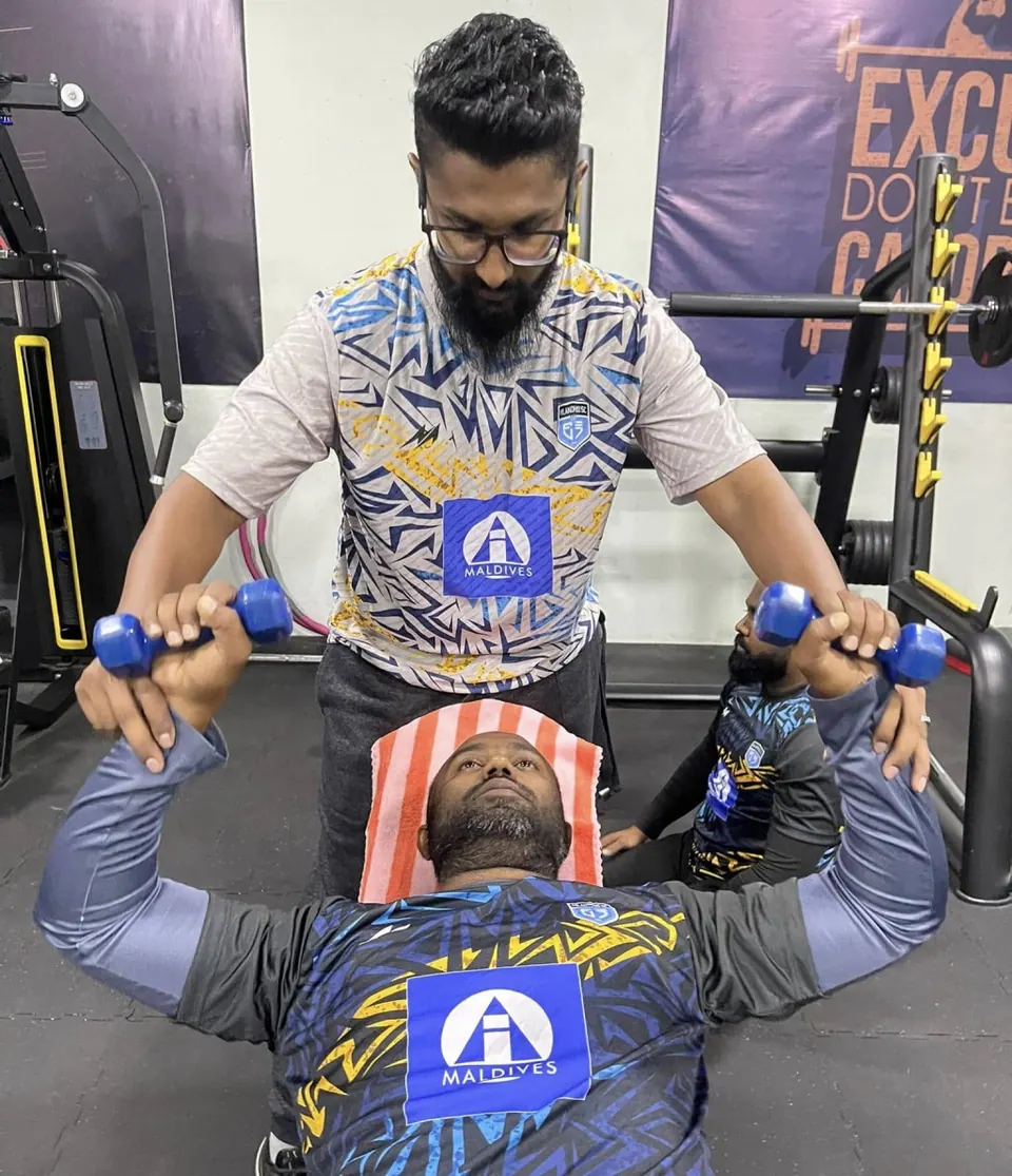 Instructor training a member on a bench inside the Milandhoo indoor gym