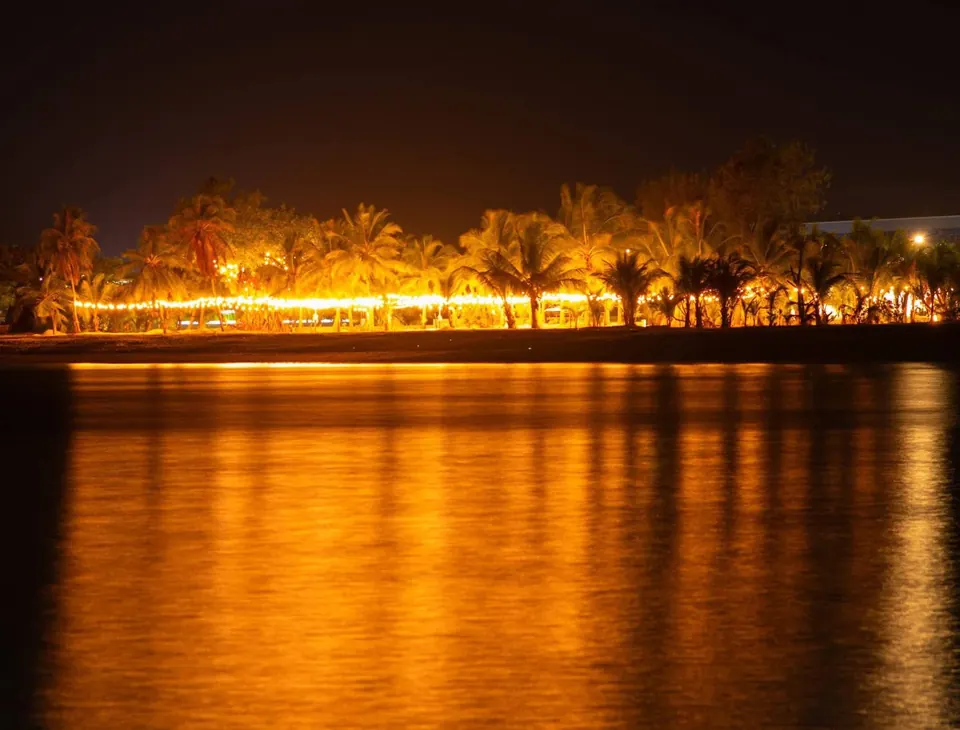 Maako Beach lit up at night, seen across the lagoon