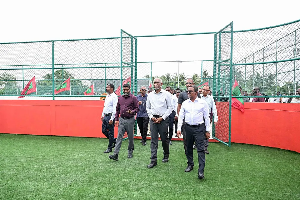 Mesh-fenced volleyball court beside the artificial-turf futsal pitch