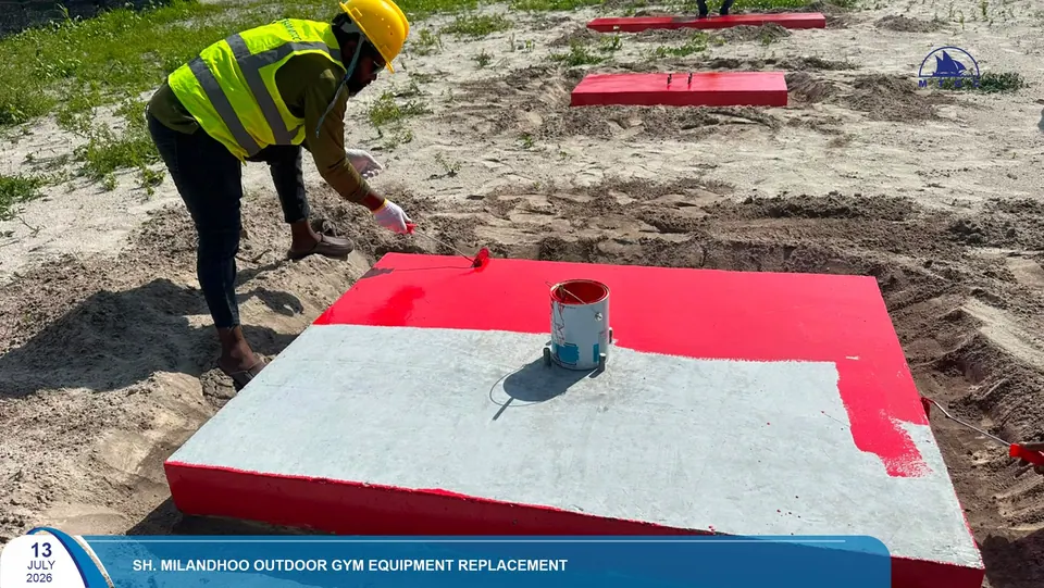 A row of red concrete bases being painted for the new outdoor gym equipment, July 2026